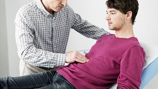 Gastroenterology consultant with hand on man's stomach