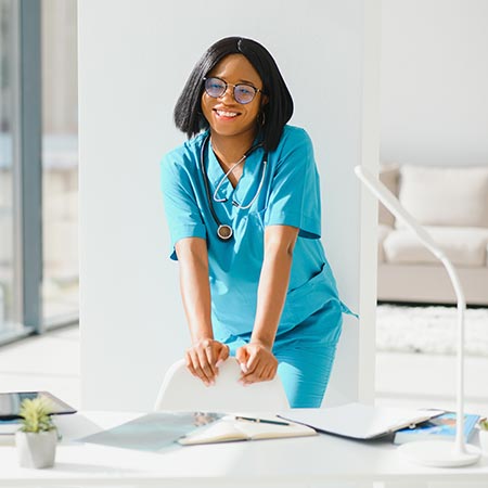 Young black nurse leaning on chair smiling