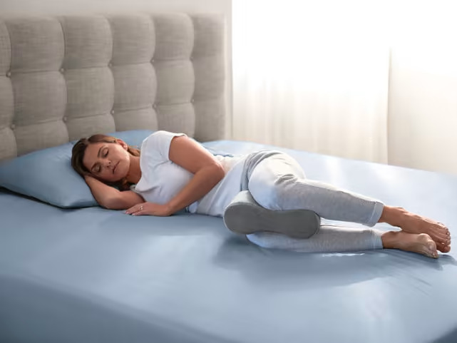 Woman sleeping on her side with a pillow between her legs