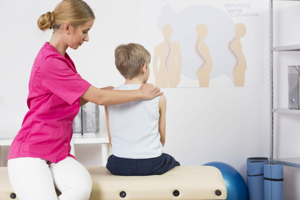 health care professional trying to improve posture of young boy