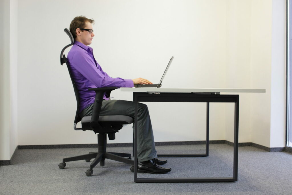 person sitting upright in their work chair
