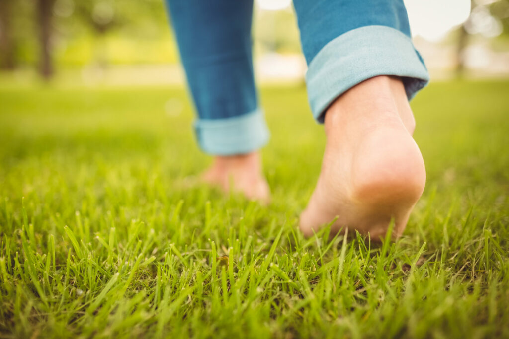 person walking barefoot in the grass