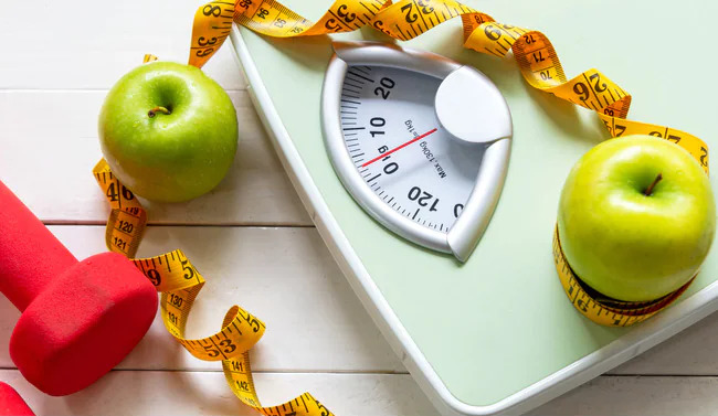 scale, dumbbells, measuring tape, and apples