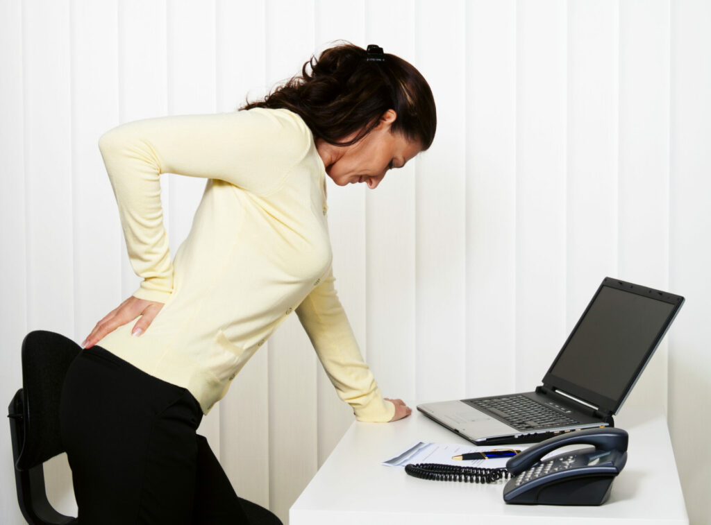 woman with back pain stretching at her desk
