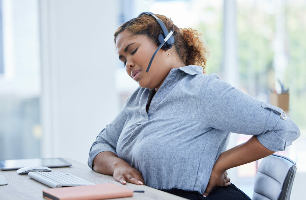 woman suffering from back pain at her desk