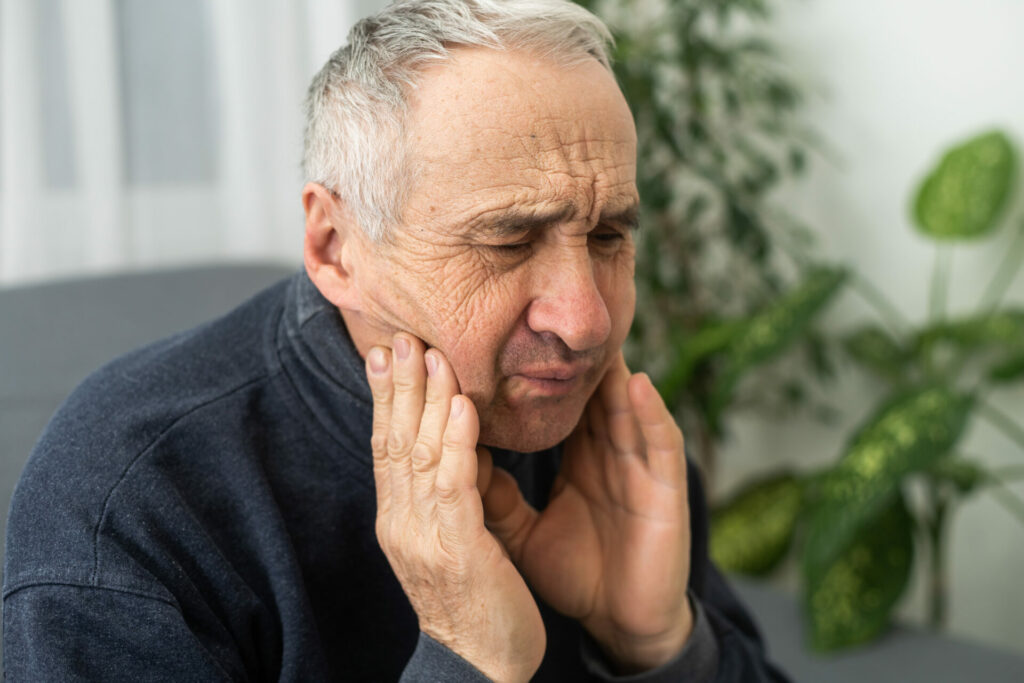 older man clutching his jaw
